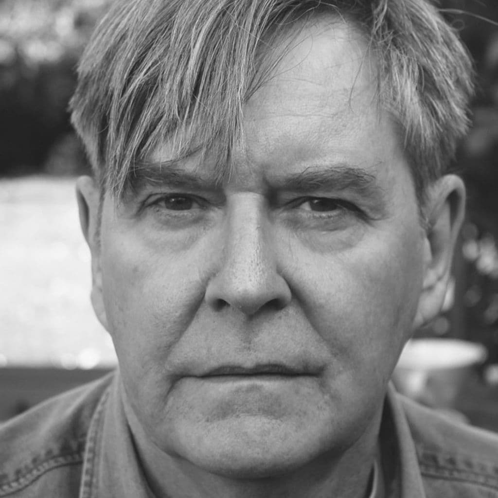 Black and white headshot of James Fleet, white man with brown hair.