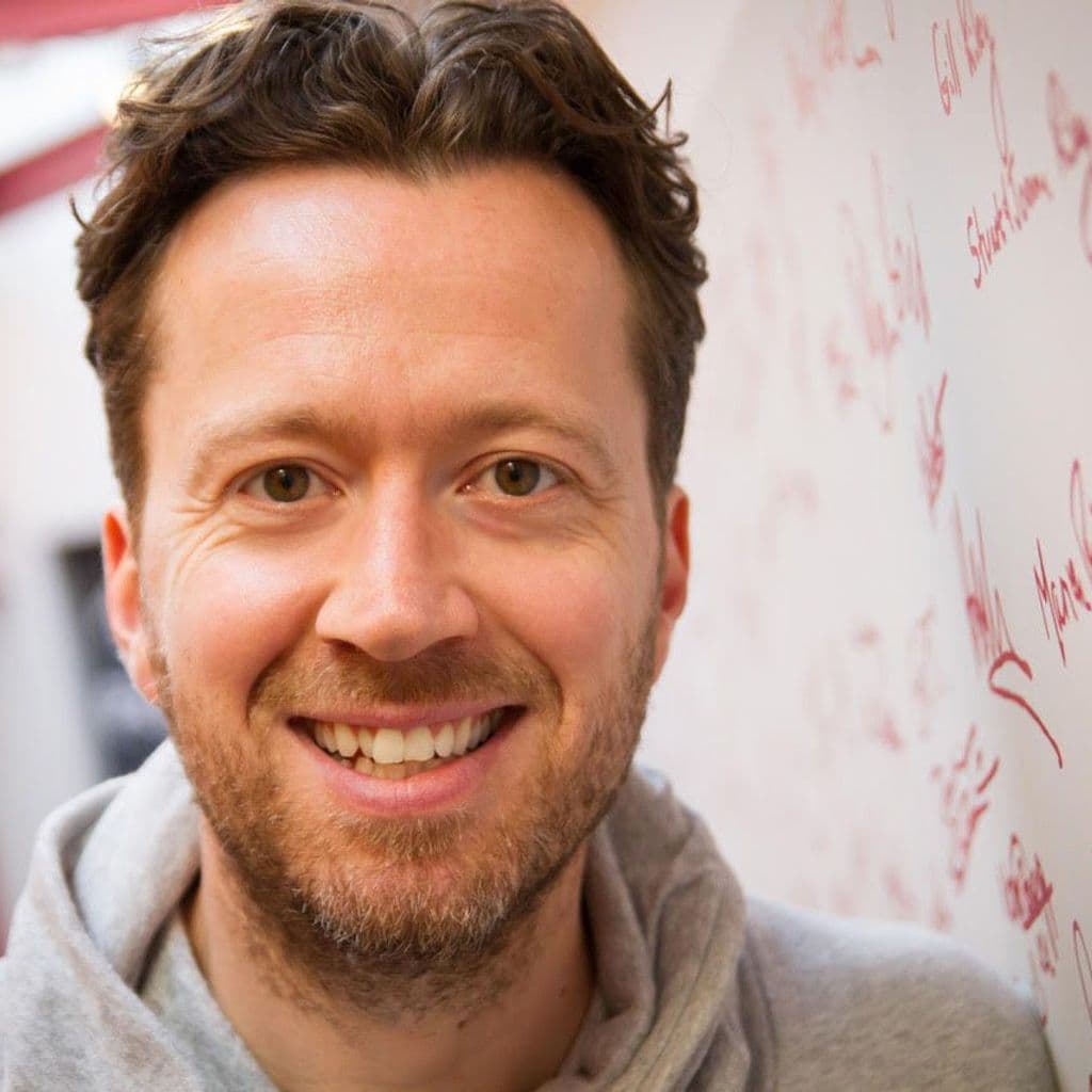 Jez Bond Headshot infront of signed wall at the Park Theatre