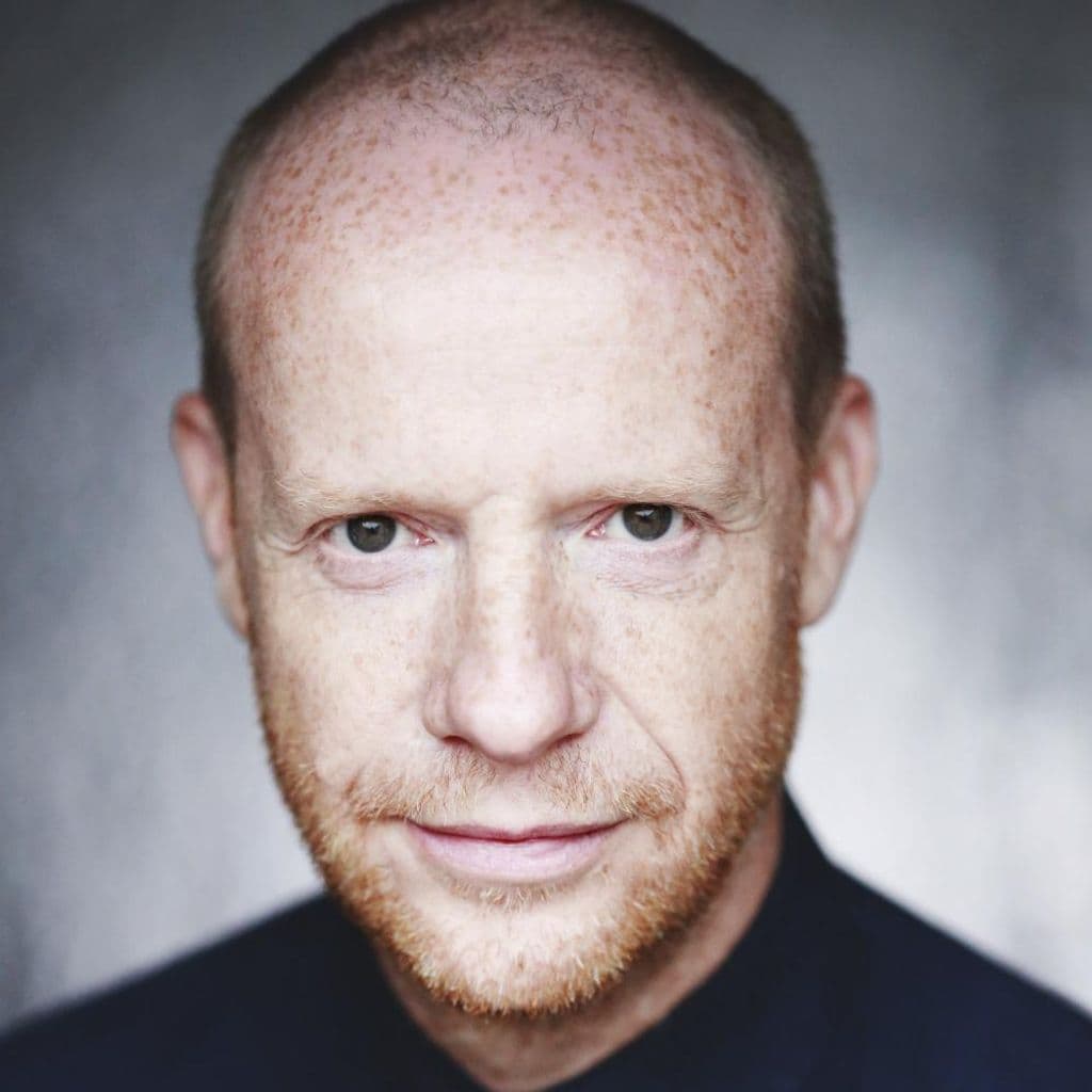 Jonathan Slinger Headshot, a white man with lots of freckles, brown eyes and a short gingery beard.