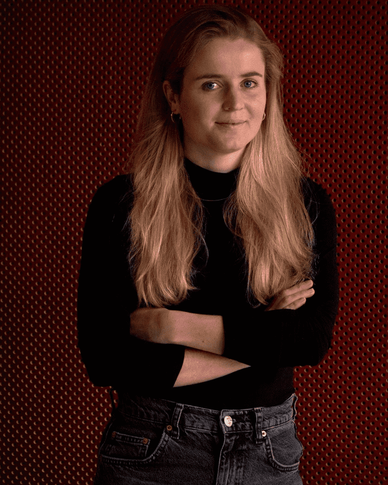 Photo of Ellie Keel with her arms crossed. Ellie is a white female with blonde hair, wearing a black jumper and jeans. She has a small gentle smile on her face.